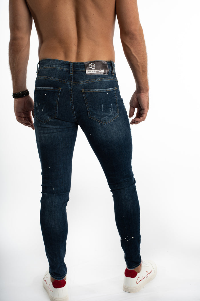 Rear view of Carbon Jeans Jaxx slim fit blue washed denim for men, featuring white paint splatter and branded waist patch.