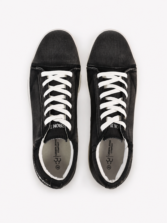 Black canvas sneakers with white laces and a minimalist design, viewed from above on a white background.