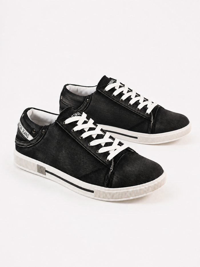 Black canvas sneakers with white laces and rubber soles, featuring a casual design and contrasting stitching.