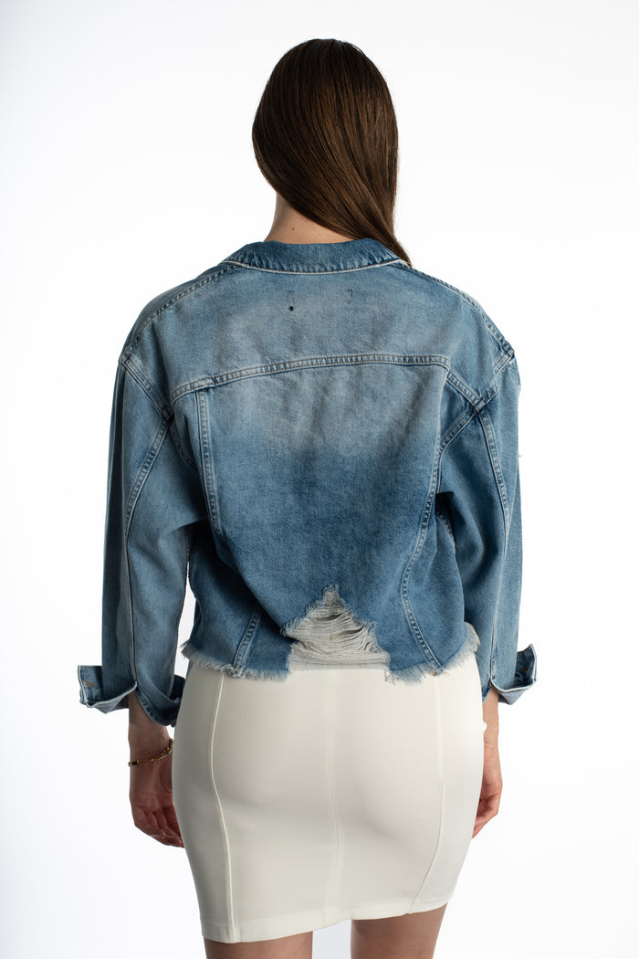 Back view of the oversized Jolie blue washed denim jacket featuring a distressed frayed hem and streetwear fit.