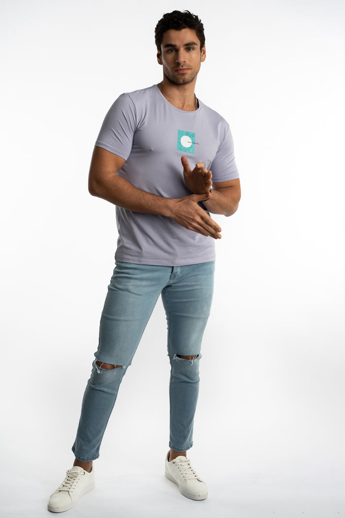 Model wearing Kolton Light Blue Slim Fit Jeans with distressed knee rips and a purple streetwear t-shirt.