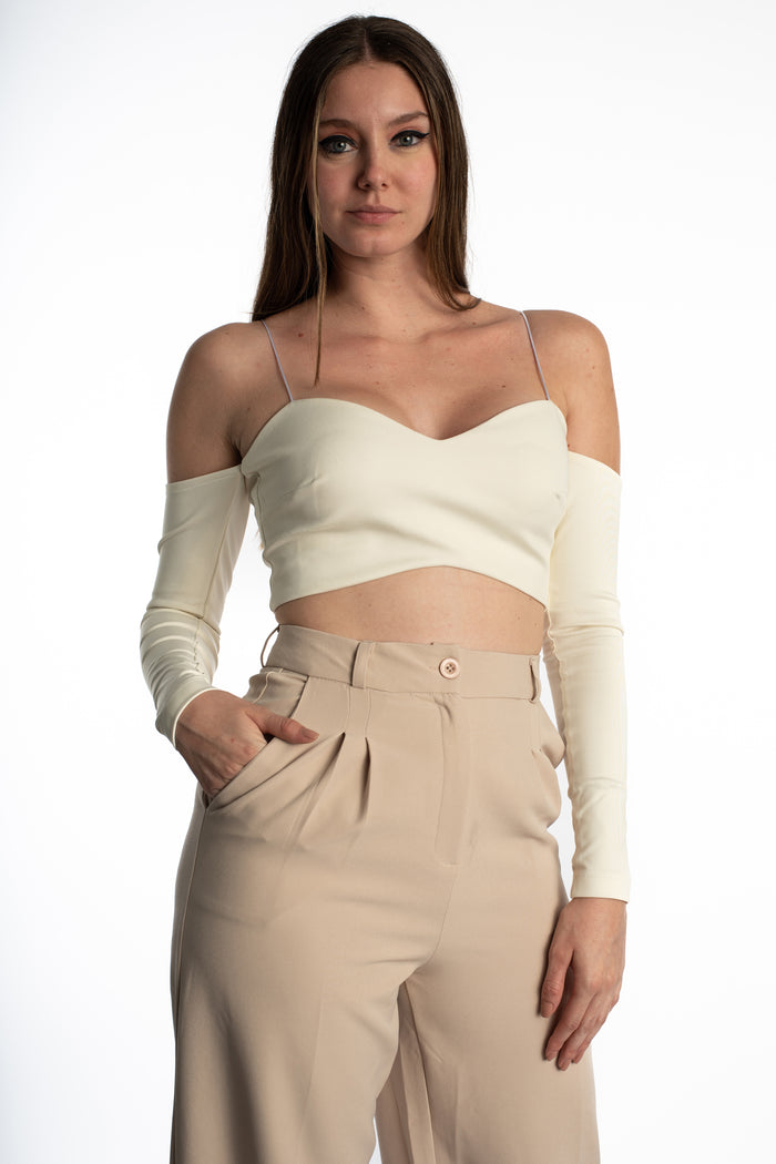 Leyla cream crop top with off-the-shoulder long sleeves and thin spaghetti straps paired with tan trousers.