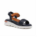 Women's blue leather sandals with tan straps and hook-and-loop closure, white cushioned sole