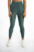 Maci high-waisted teal leggings in sleek athletic fabric, styled with white sneakers for an urban athleisure look.
