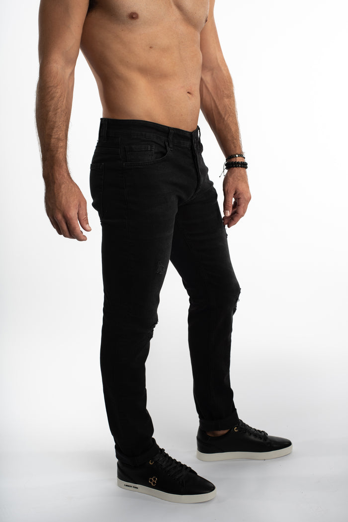 Side view of Mason slim straight black streetwear jeans with subtle knee distressing on a model.