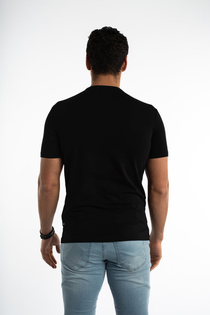 Back view of a man wearing the Carbon Memories Graphic T-Shirt in black with a regular fit and light wash denim jeans.