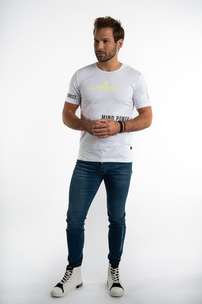 Man in white Mind Power graphic streetwear t-shirt and blue slim-fit jeans against a white background.