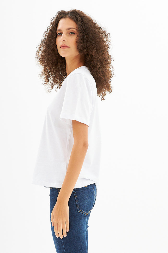 Side view of Carbon's white More Love graphic t-shirt in premium cotton, styled with blue denim streetwear jeans.