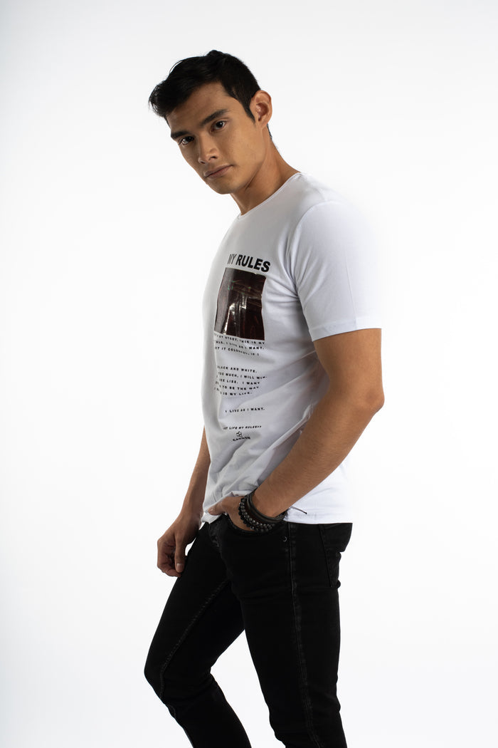 Male model in a white My Rules Graphic Streetwear Tee and black jeans, showcasing an urban OOTD aesthetic.
