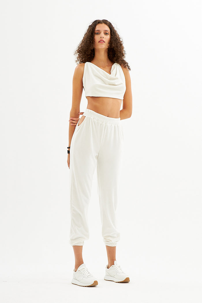 Model in Natalie white two-piece streetwear set with cowl neck crop top and hip cut-out joggers co-ord.