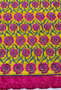 Close-up of Swiss cotton voile lace fabric featuring a pattern with pink and blue floral designs on a yellow background.