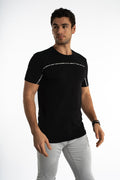 Model in Reflect Your Style carbon black streetwear graphic tee with white text chest detail and light gray pants.