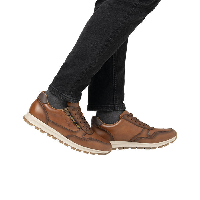 Men's brown sneakers with side zipper and lace-up, worn with dark jeans