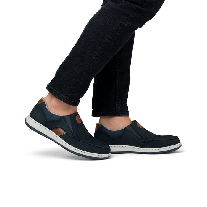 Men's dark blue slip-on sneakers on feet with jeans and low white sole