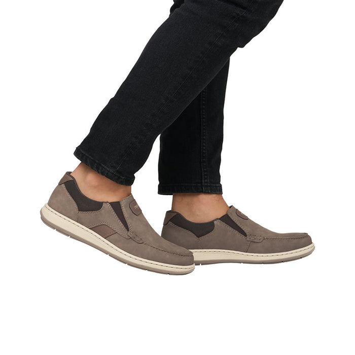 Men's taupe slip-on sneakers on feet with jeans and white rubber sole