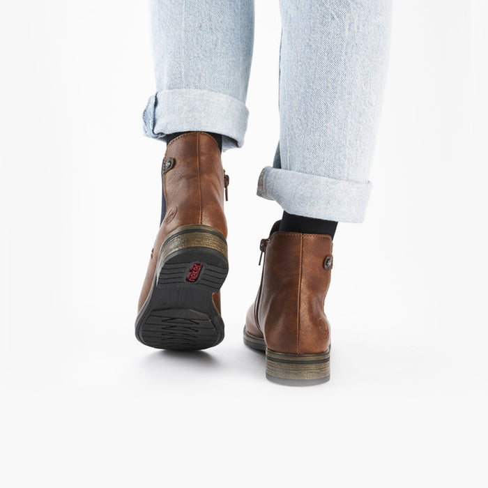Brown ankle boots with stacked heel and pull tab, worn with light jeans