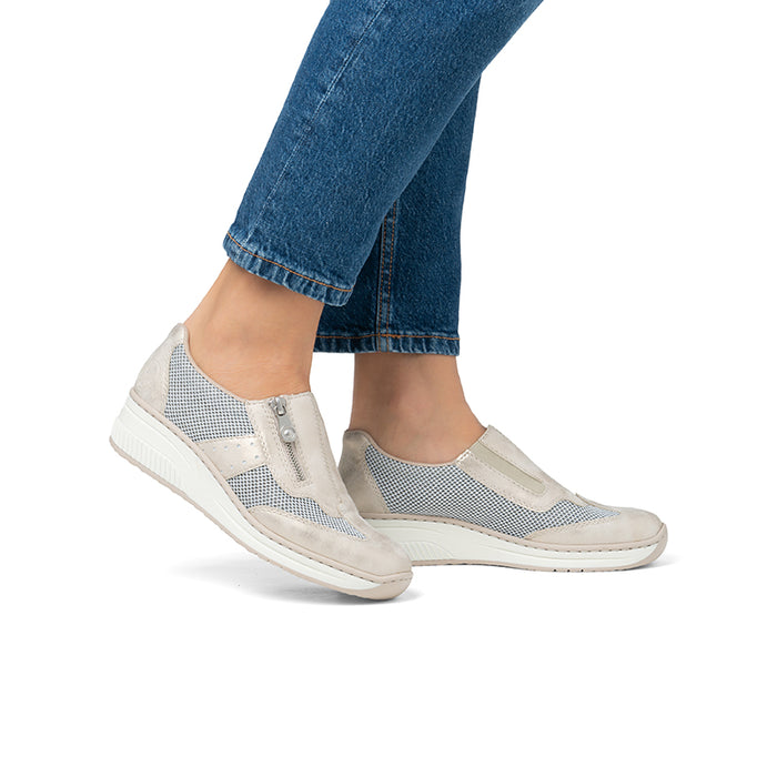 Beige low-top loafers with mesh panels worn with blue jeans