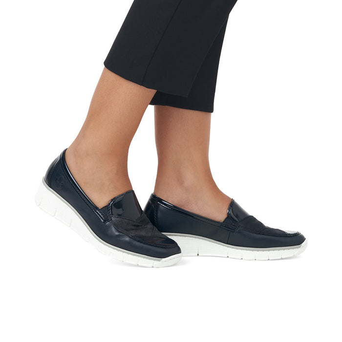 Navy slip-on loafers with cushioned collar and white outsole, worn with cropped pants