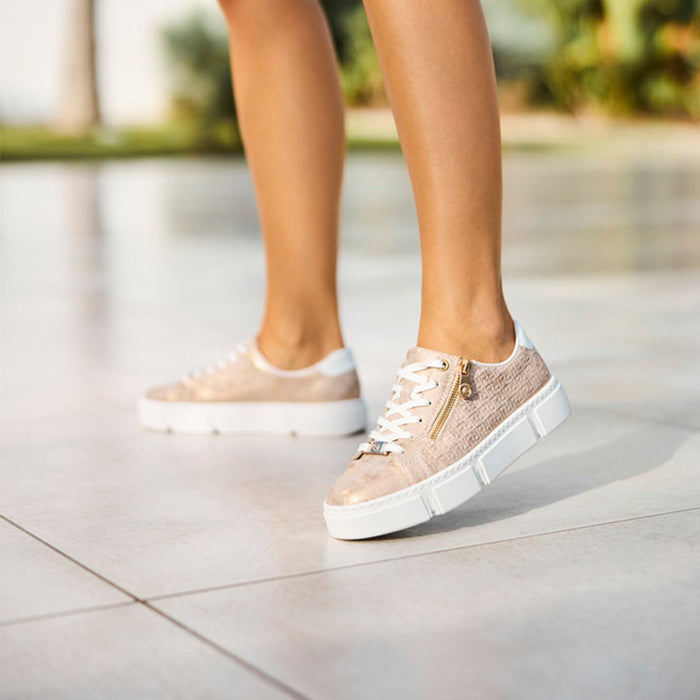 Rieker women's sneakers on feet, blush metallic with white sole and lace-up