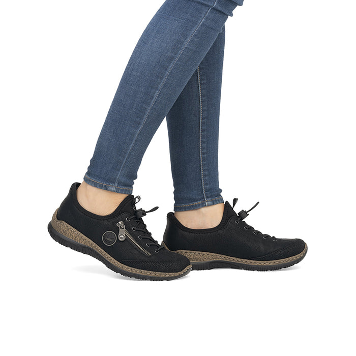 Black women's slip-on sneaker worn with blue jeans, lace-up and textured sole