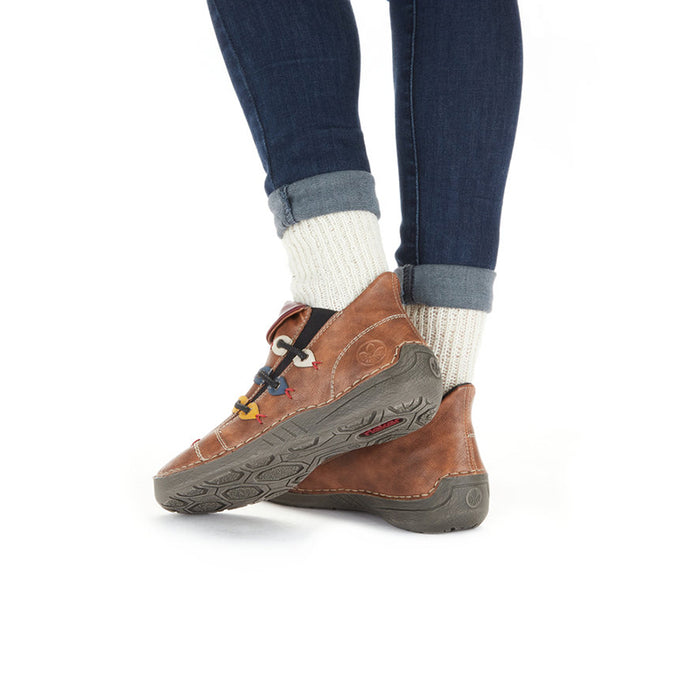 Brown sneaker on foot with textured outsole and laces