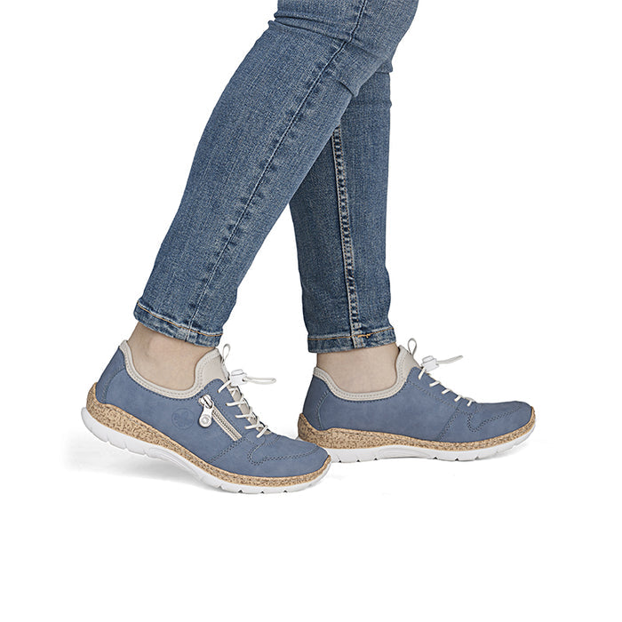 Blue slip-on walking shoes on model with white laces and cork-textured outsole