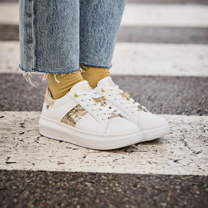 White lace-up sneakers with glitter side panel worn with blue jeans