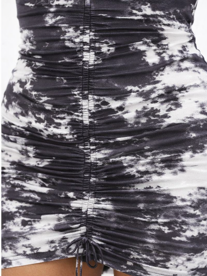 Close-up of a ruched black and white dress featuring a tie detail, showcasing a cloud-like pattern and textured fabric.