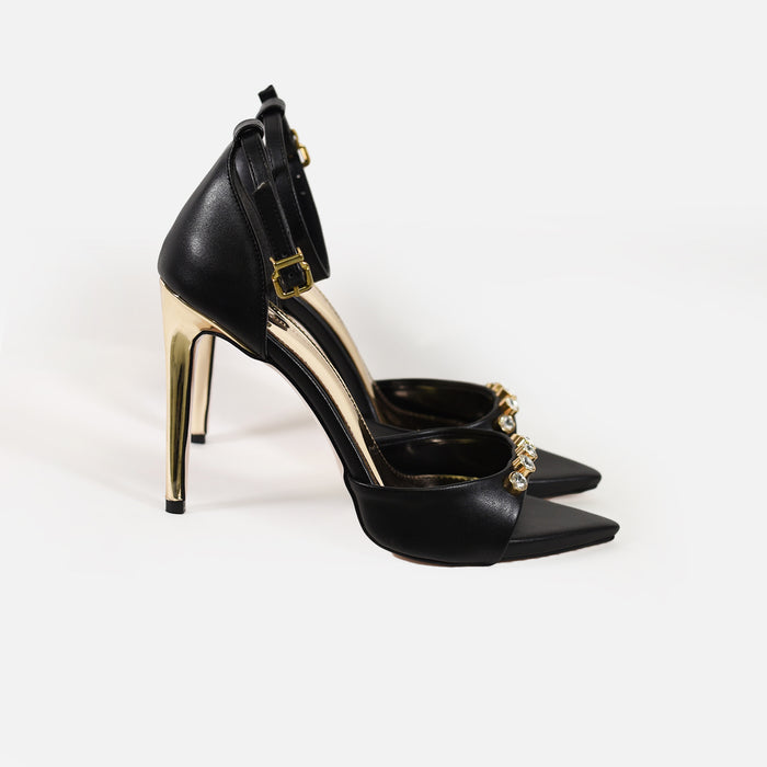 Rock black pointed toe heels with metallic gold stiletto, rhinestone embellishments, and ankle straps on white background.