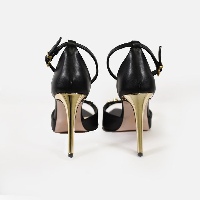 Rear view of Rock Black Pointed Toe Heels featuring metallic gold stiletto heels and adjustable buckled ankle straps.