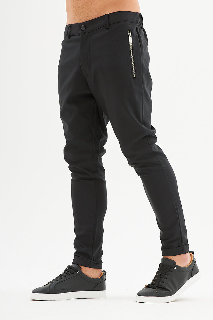 Men's Ronald black slim fit streetwear pants with silver side zipper pocket and tapered leg with black sneakers.