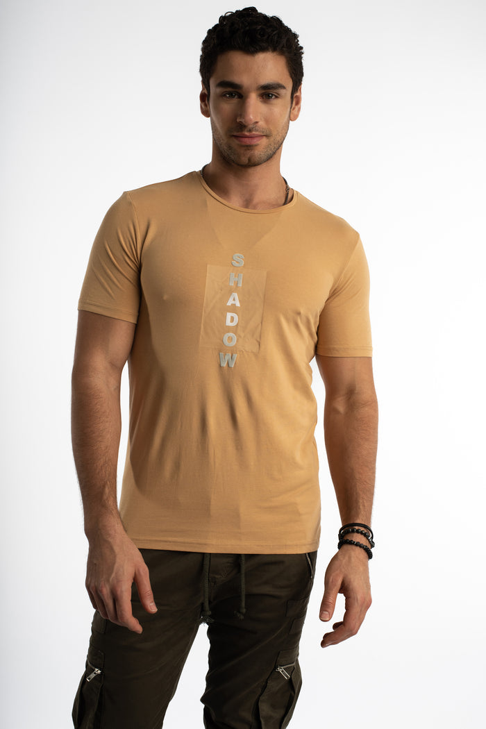 Men's Shadow Oversized Graphic Tee in mink tan, featuring a vertical streetwear logo on a clean studio background.
