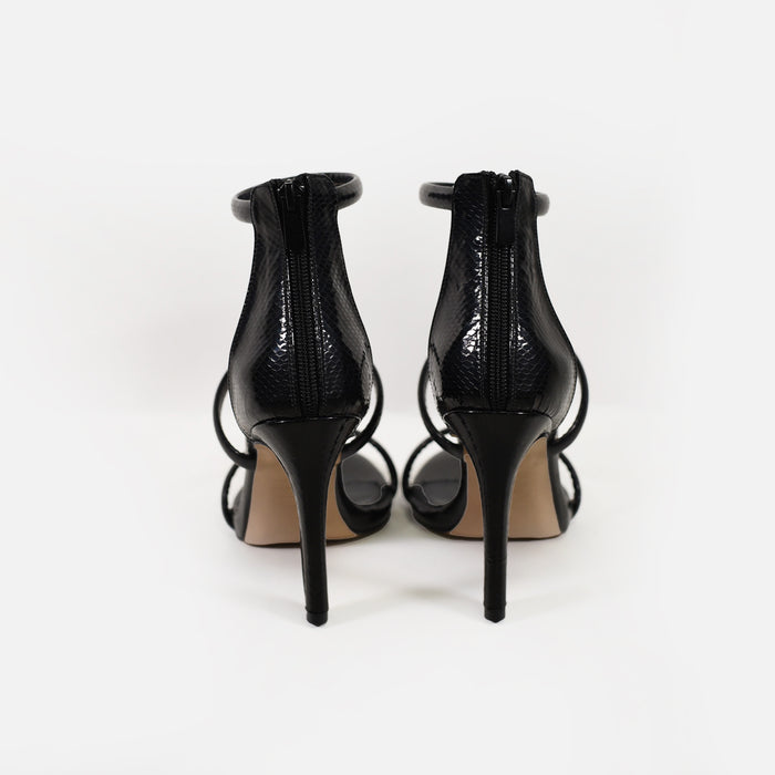 Rear view of black snakeskin stiletto pumps by Carbon featuring a back zipper closure and high heels.