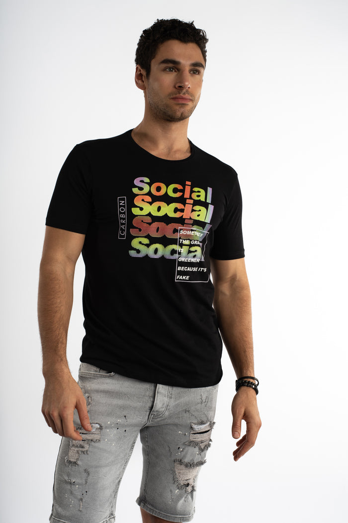 Model in carbon black Social Graphic Streetwear Tee with rainbow text and distressed grey denim shorts.