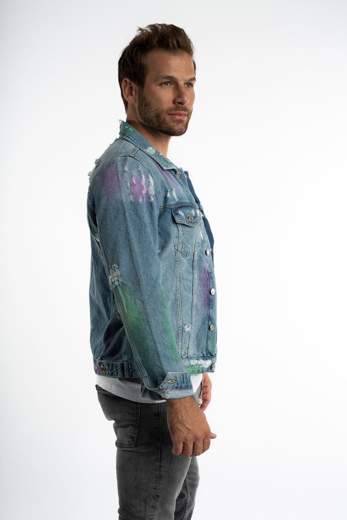 Side view of Stardust blue washed distressed denim jacket with colorful paint splatter and streetwear aesthetic.