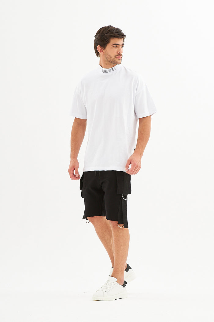 Man in black Tommy Denim cargo shorts with metal hardware, paired with a white streetwear t-shirt and white sneakers.