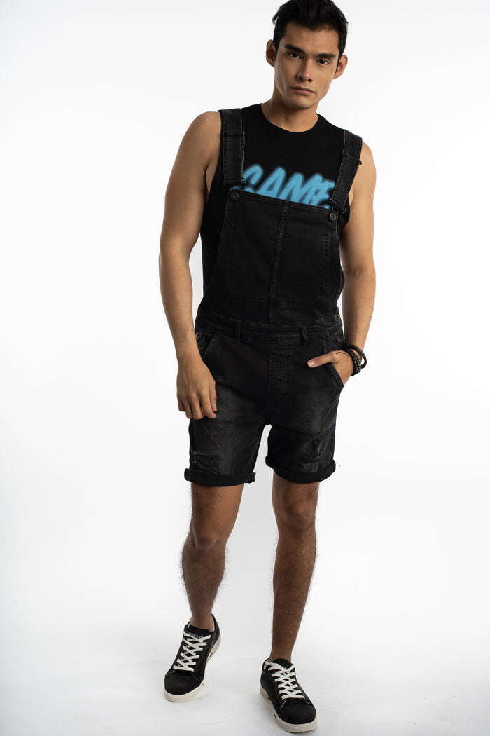 Men's Wayne black denim overalls with distressed short legs and streetwear fit over a black graphic tank top.