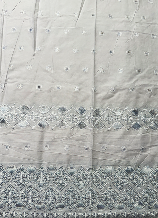 A piece of white Swiss Voile lace fabric with a delicate floral pattern and eyelet cut-outs.