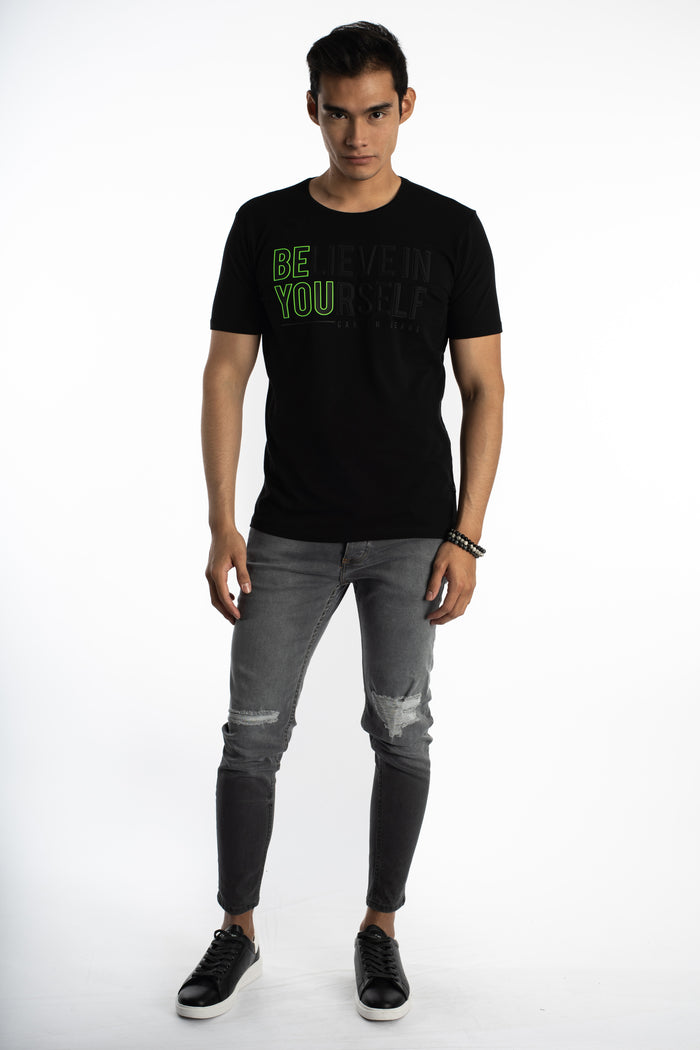 Man wearing Carbon Zayn slim fit grey distressed denim jeans and black graphic t-shirt on a white background.